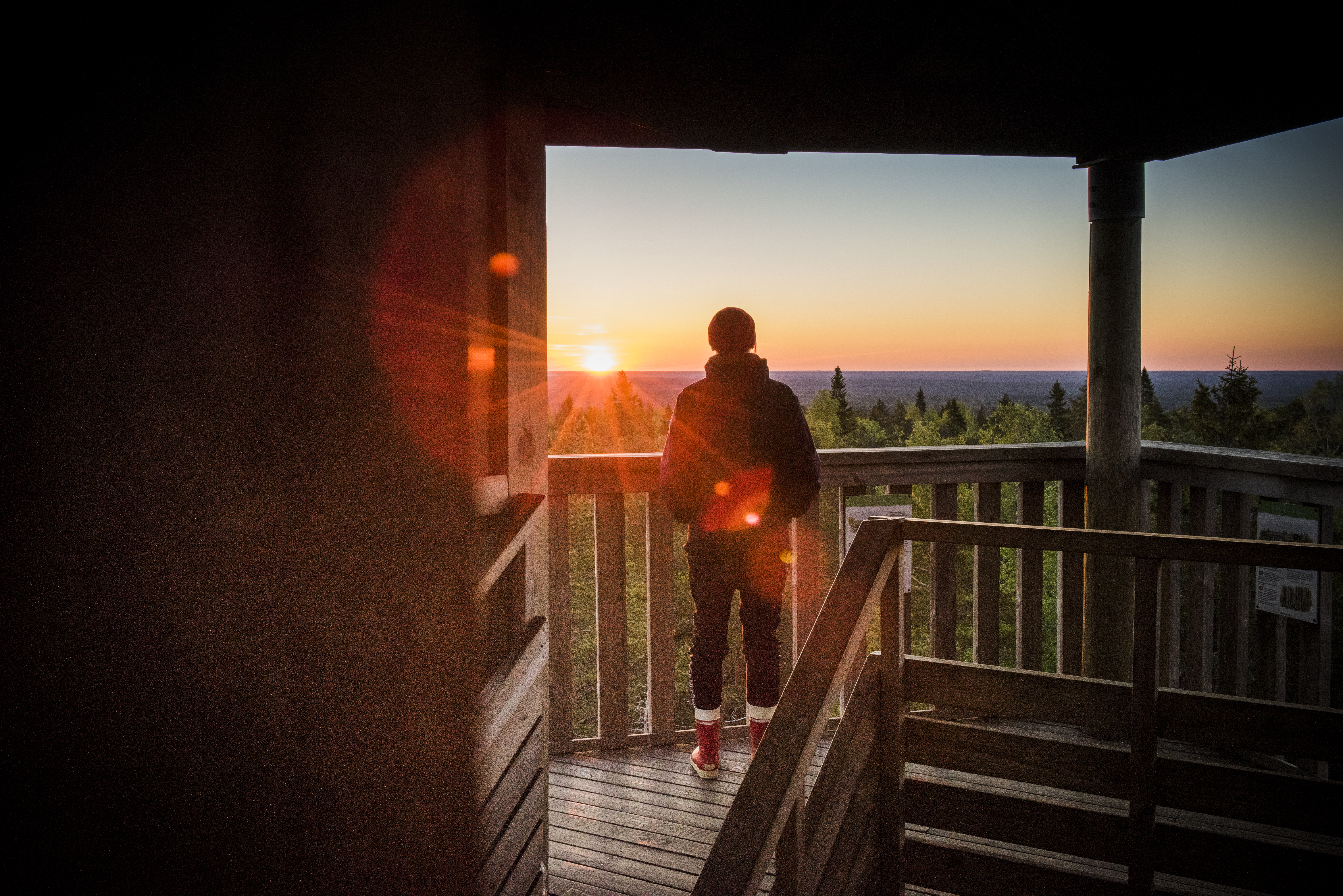 Henkilö katselee maisemia Lauhanvuoren näkötornissa ilta-auringossa