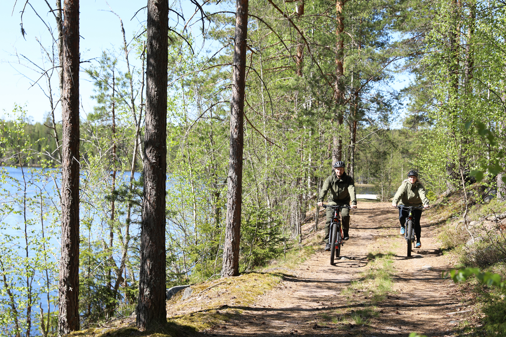 Maastopyöräilijöitä järvenrantamaisemissa aurinkoisena kevätpäivänä