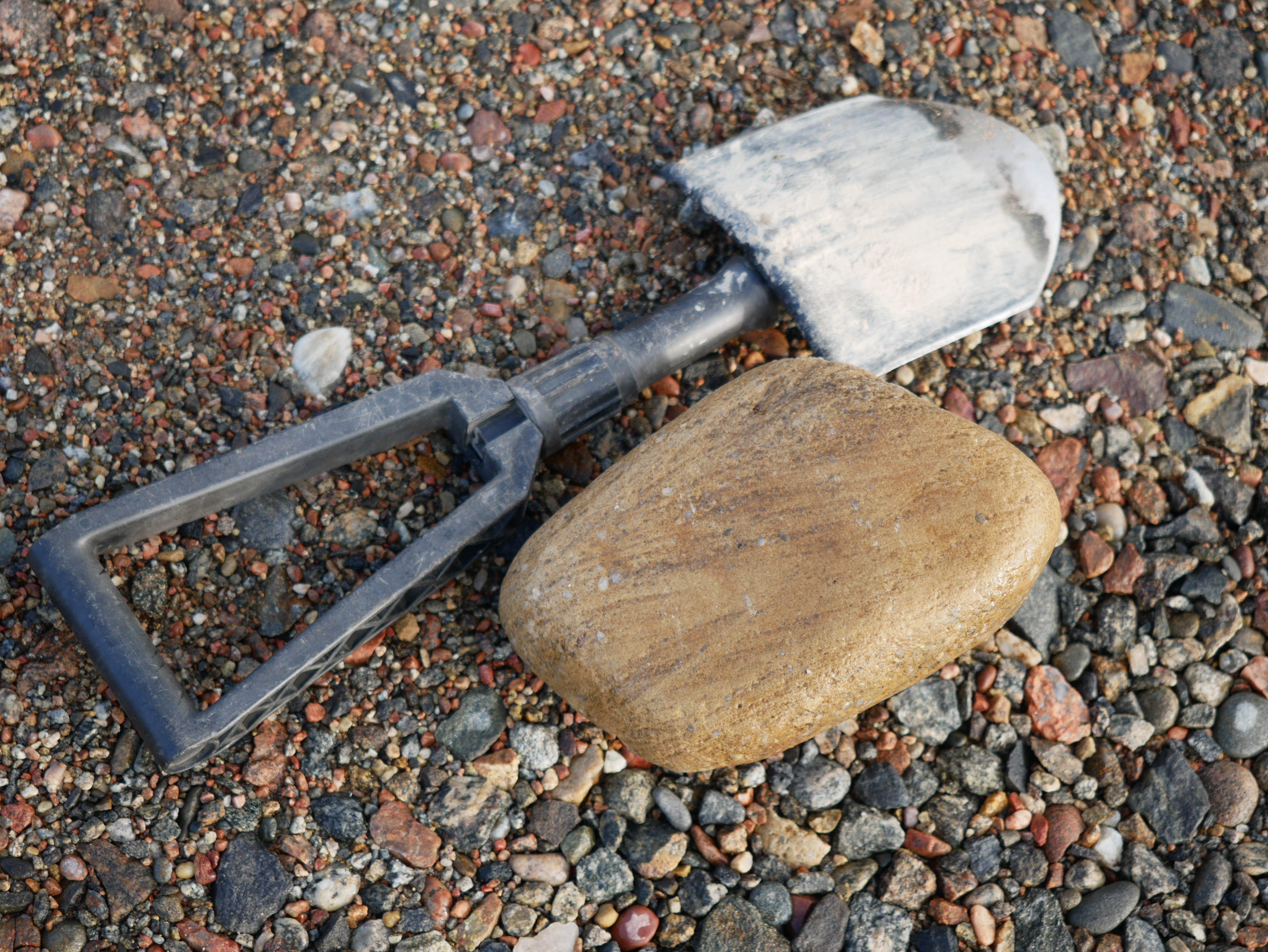 Kenttälapio ja pyöristynyt kivi sorapatjan päällä