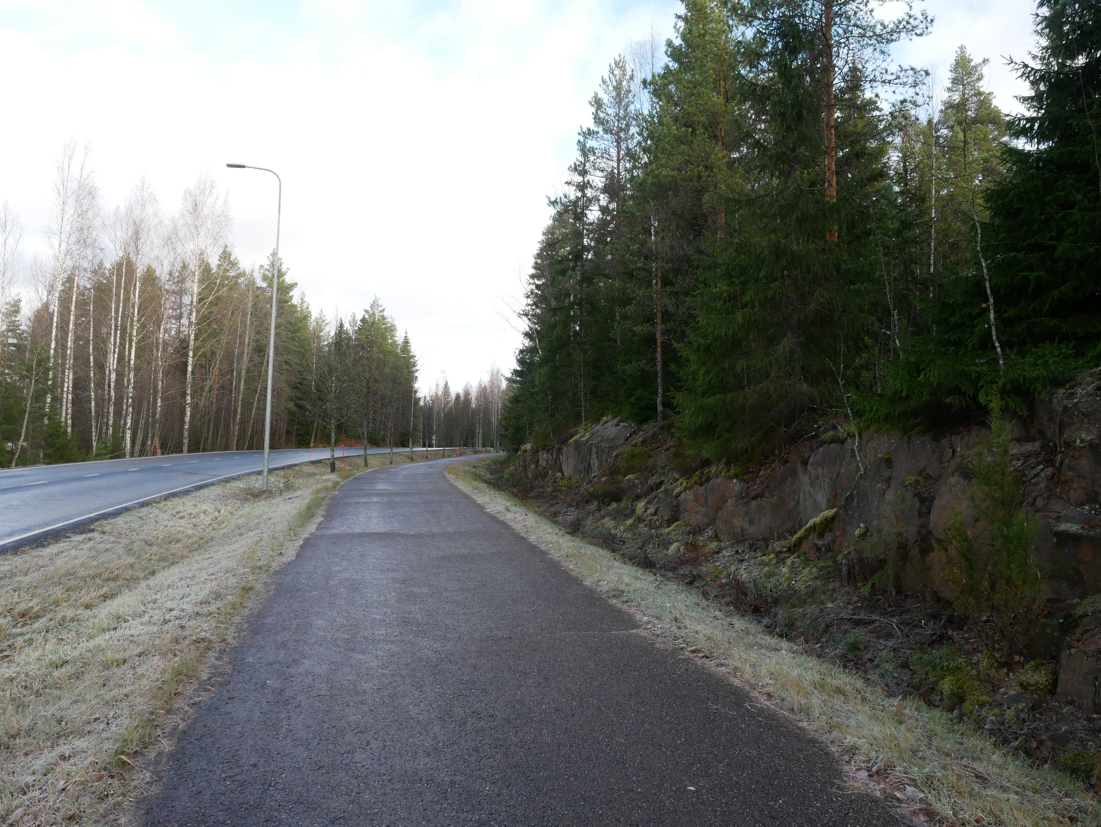 Kevyen liikenteen väylä maantien laidassa, tiealueen reunalla kallioleikkaus .